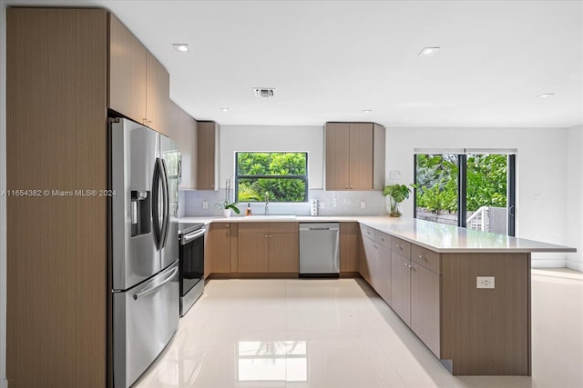 kitchen featuring a wealth of natural light, kitchen peninsula, appliances with stainless steel finishes, and decorative backsplash