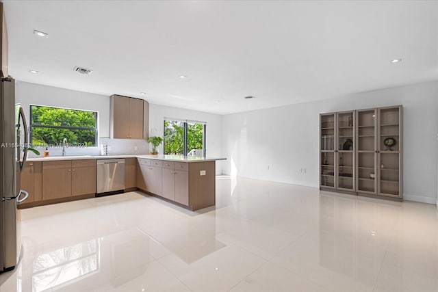 kitchen featuring stainless steel appliances, sink, kitchen peninsula, and light tile patterned flooring