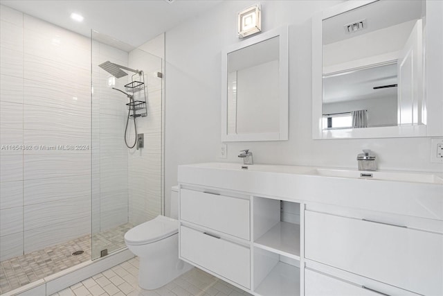 bathroom featuring vanity, toilet, a tile shower, and tile patterned flooring