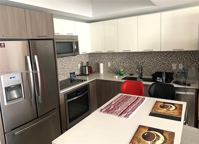 kitchen featuring backsplash, sink, appliances with stainless steel finishes, and white cabinetry