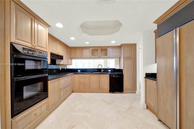 kitchen with light brown cabinetry, a tray ceiling, sink, black appliances, and dark stone countertops