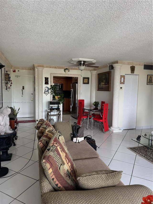 living room featuring decorative columns, a textured ceiling, light tile patterned floors, and ceiling fan