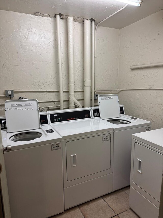 clothes washing area featuring washer and clothes dryer and light tile patterned flooring