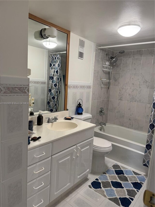 full bathroom featuring tile patterned floors, shower / bathtub combination with curtain, toilet, tile walls, and vanity