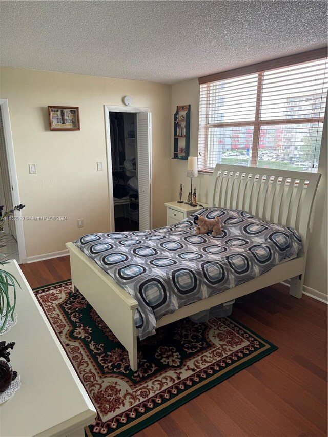 bedroom with a textured ceiling, a closet, and wood-type flooring