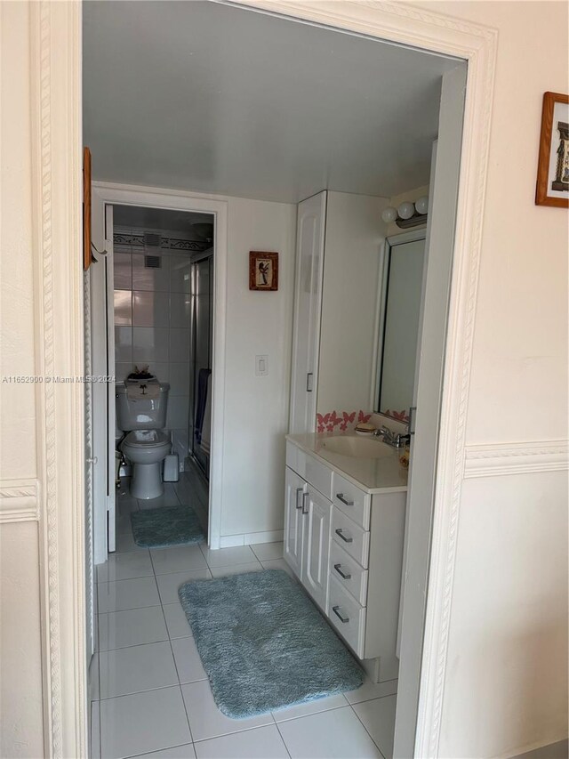 bathroom with vanity, toilet, an enclosed shower, and tile patterned floors