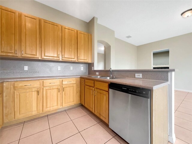 kitchen featuring light tile patterned floors, dishwasher, kitchen peninsula, and sink