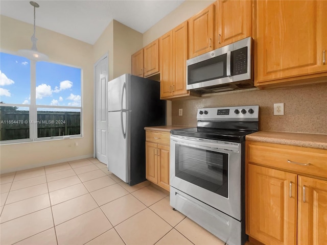 kitchen featuring decorative light fixtures, appliances with stainless steel finishes, light tile patterned floors, and backsplash