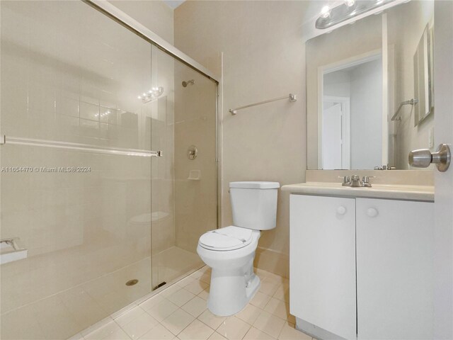 bathroom featuring a shower with door, vanity, toilet, and tile patterned flooring