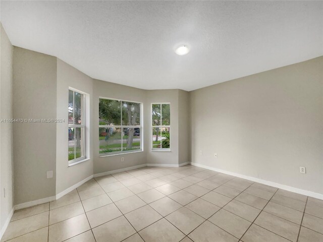 spare room featuring a textured ceiling and light tile patterned flooring