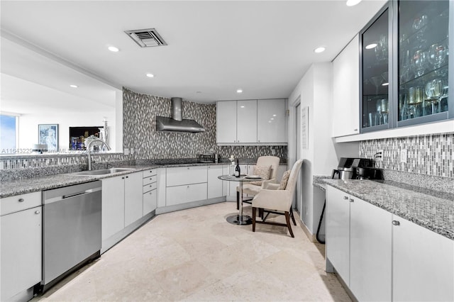 kitchen featuring dishwasher, wall chimney range hood, backsplash, sink, and white cabinetry