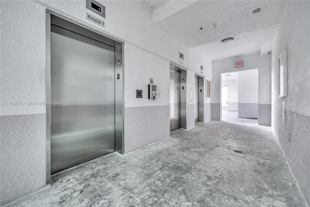 corridor with a textured ceiling and elevator