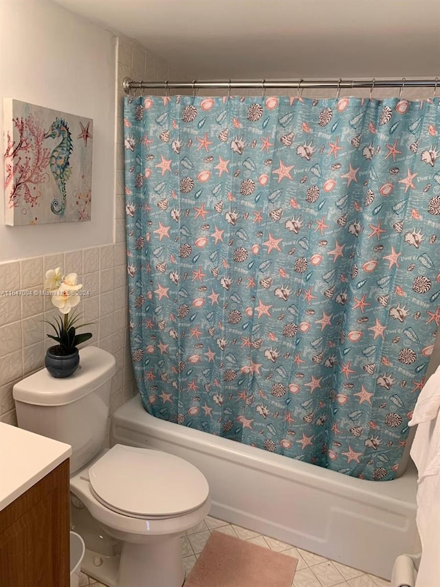 full bathroom with toilet, tile patterned floors, vanity, shower / bath combo with shower curtain, and tile walls