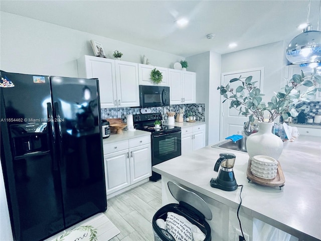 kitchen featuring white cabinets, decorative backsplash, black appliances, light wood-type flooring, and decorative light fixtures