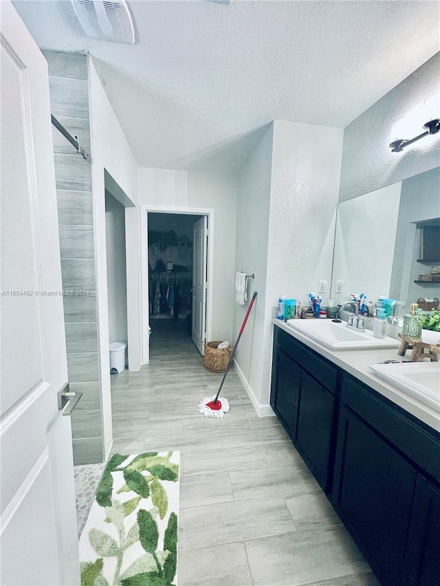 bathroom featuring a shower, vanity, a textured ceiling, and wood-type flooring