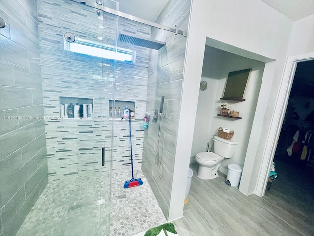 bathroom with hardwood / wood-style flooring, toilet, and walk in shower