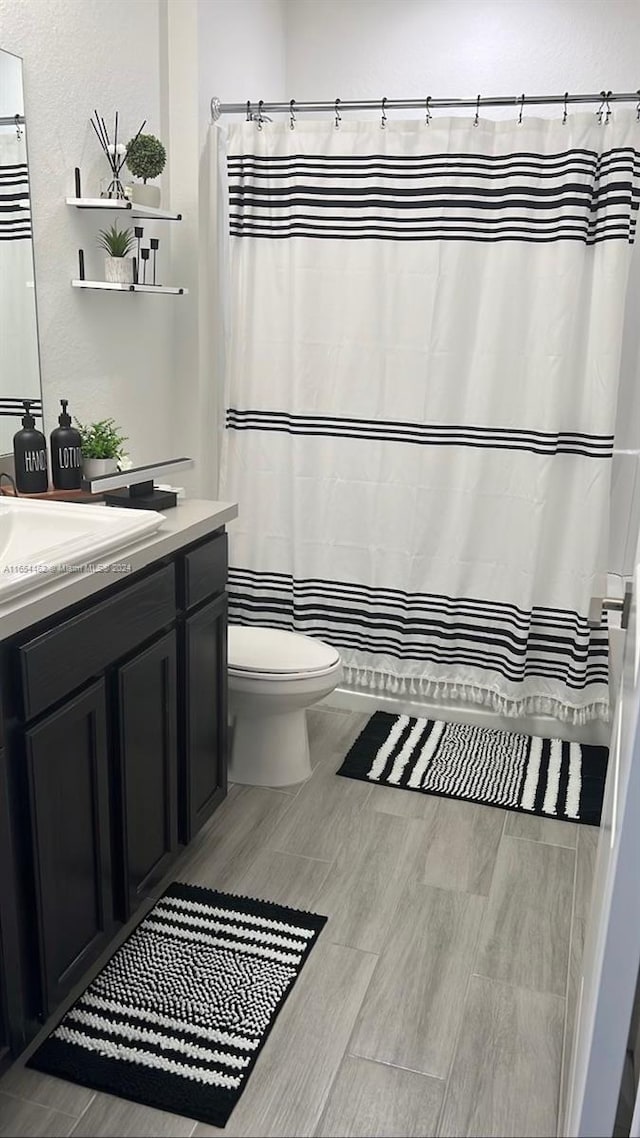 bathroom featuring wood-type flooring, vanity, and toilet