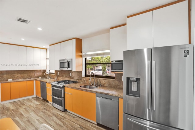 kitchen featuring light wood-type flooring, stainless steel appliances, white cabinetry, and sink