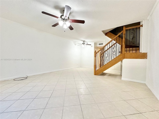 spare room featuring a textured ceiling, ceiling fan, and light tile patterned floors