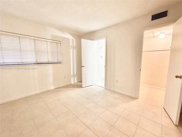 8650 SW 67th Ave Unit 1032, Pinecrest, FL 33156 - unfurnished bedroom with a walk in closet, light tile patterned flooring, a closet, and baseboards