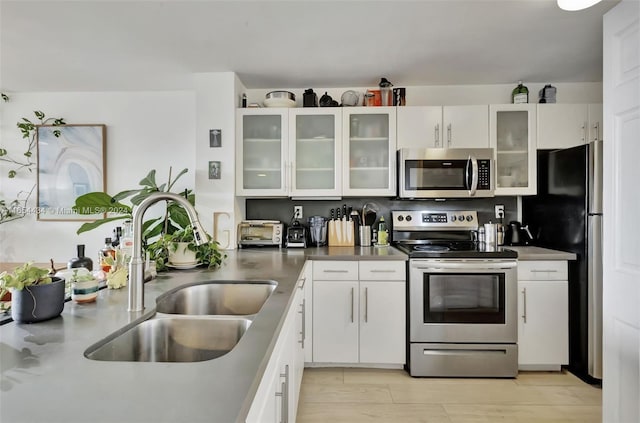 kitchen with appliances with stainless steel finishes, sink, and white cabinets