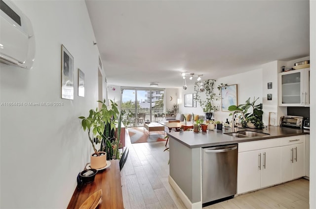 kitchen featuring light hardwood / wood-style flooring, dishwasher, kitchen peninsula, sink, and white cabinets