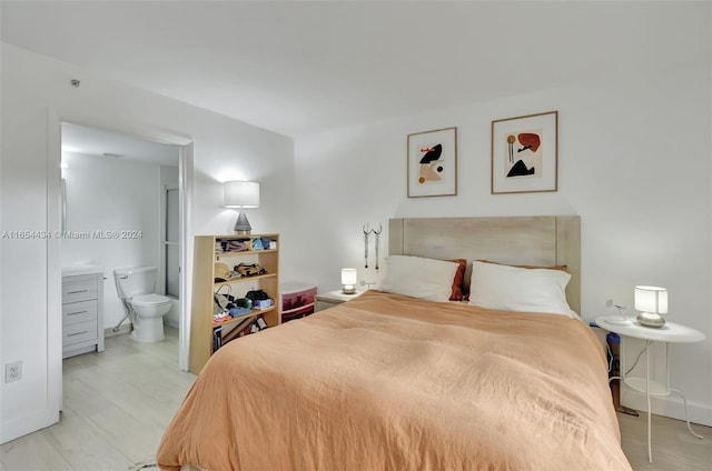 bedroom featuring ensuite bath and light wood-type flooring