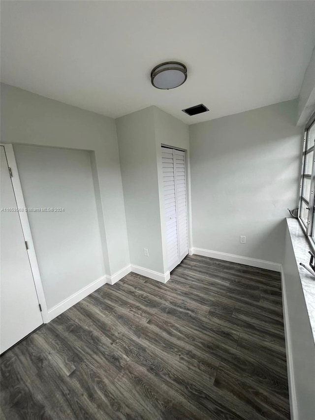 unfurnished bedroom with dark hardwood / wood-style floors and a closet