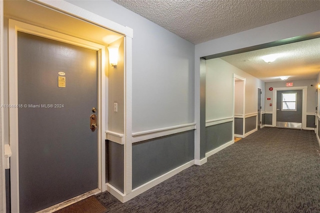 corridor featuring a textured ceiling and carpet flooring