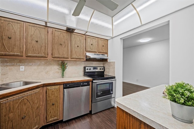 kitchen featuring dark wood-type flooring, ceiling fan, stainless steel appliances, and tasteful backsplash