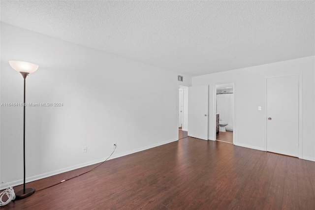 empty room with dark hardwood / wood-style floors and a textured ceiling