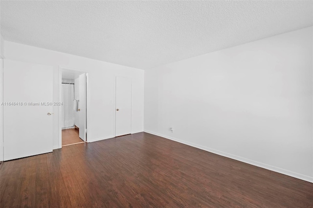 unfurnished bedroom featuring ensuite bath, dark hardwood / wood-style flooring, and a textured ceiling