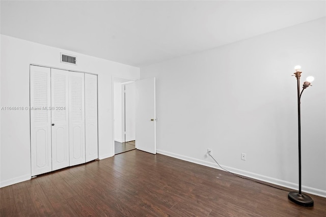 unfurnished bedroom with dark wood-type flooring and a closet