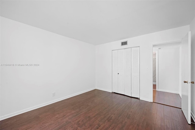 unfurnished bedroom with dark wood-type flooring and a closet