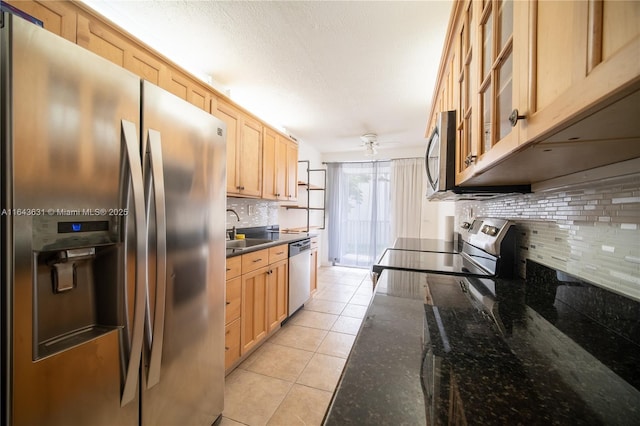 kitchen featuring light tile patterned floors, a sink, stainless steel appliances, light brown cabinetry, and backsplash