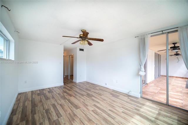 spare room featuring a ceiling fan, baseboards, visible vents, and wood finished floors