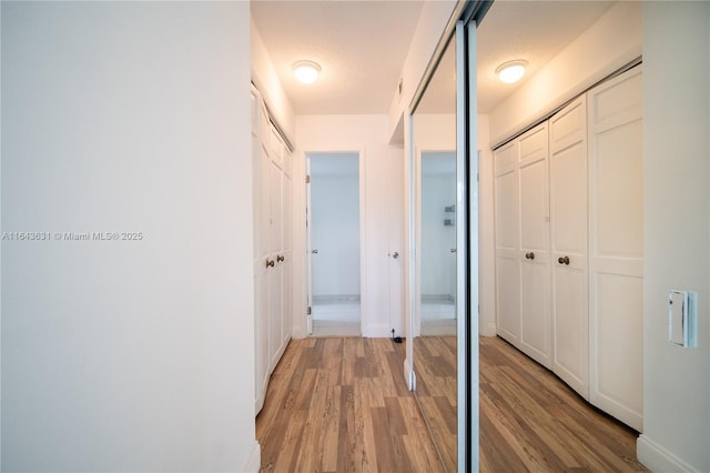 corridor with light wood-style flooring and baseboards