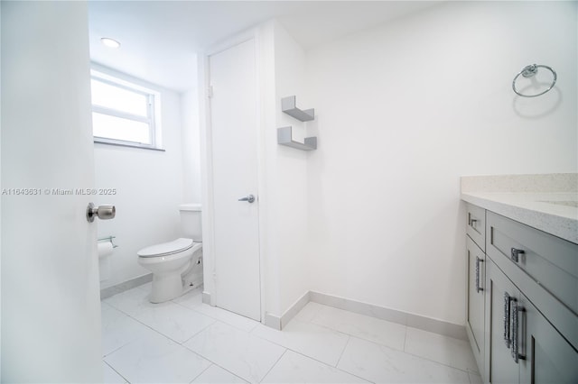 bathroom featuring marble finish floor, baseboards, vanity, and toilet