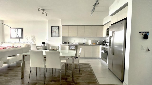 kitchen featuring appliances with stainless steel finishes, tile patterned flooring, sink, white cabinetry, and rail lighting