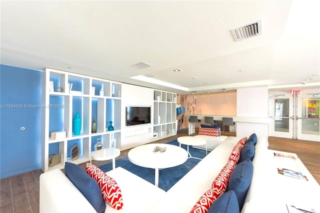 living room featuring a tray ceiling and dark hardwood / wood-style flooring