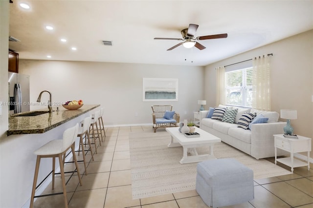 tiled living room with ceiling fan and sink