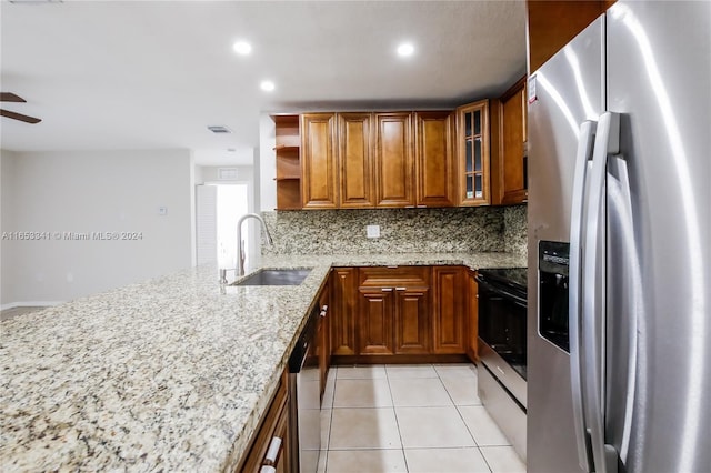 kitchen with backsplash, appliances with stainless steel finishes, light stone counters, sink, and ceiling fan