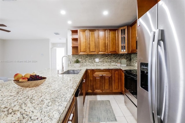 kitchen featuring ceiling fan, sink, stainless steel appliances, and light stone countertops