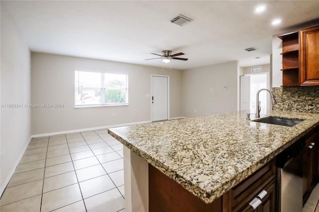 kitchen featuring stainless steel dishwasher, sink, decorative backsplash, ceiling fan, and light stone counters