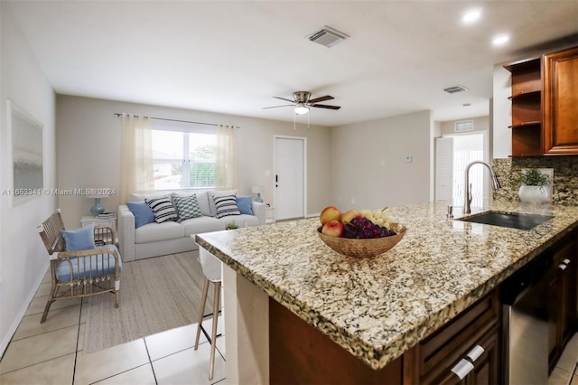 kitchen featuring sink, light stone countertops, ceiling fan, decorative backsplash, and stainless steel dishwasher