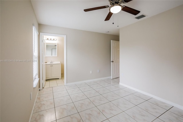 unfurnished bedroom featuring ceiling fan, sink, light tile patterned floors, and ensuite bathroom