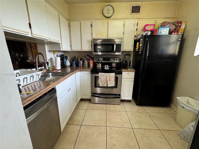 kitchen with stainless steel appliances, sink, light tile patterned floors, and white cabinets