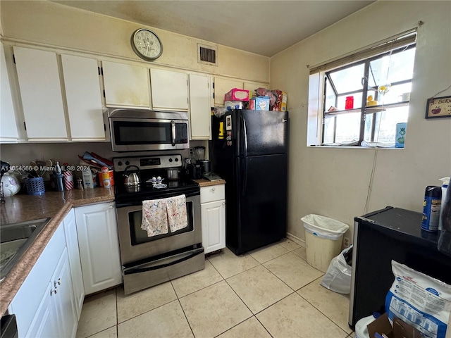 kitchen with appliances with stainless steel finishes, light tile patterned floors, and white cabinets