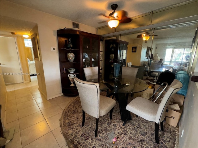 dining space with a textured ceiling, light tile patterned flooring, and ceiling fan