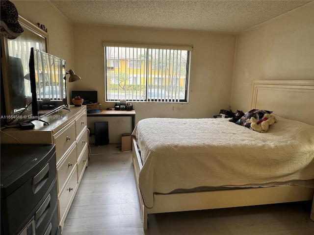 bedroom with a textured ceiling and light hardwood / wood-style flooring